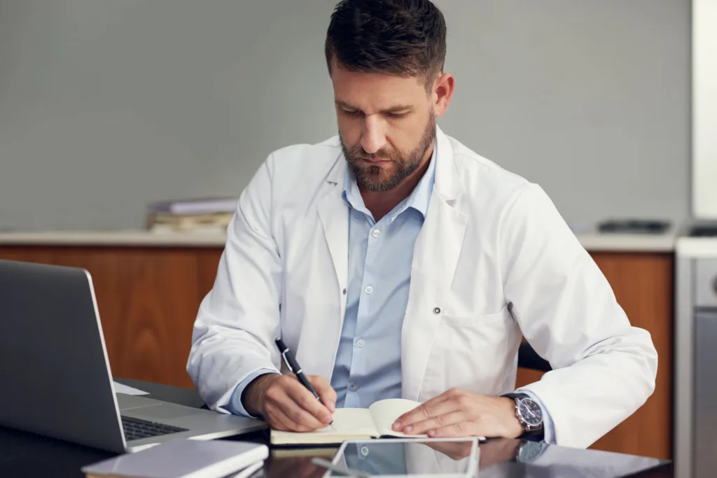 medico en consulta escribiendo una receta